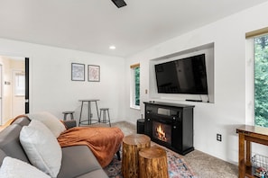 A modern living room with a fireplace, a sofa, a TV, and a small table.