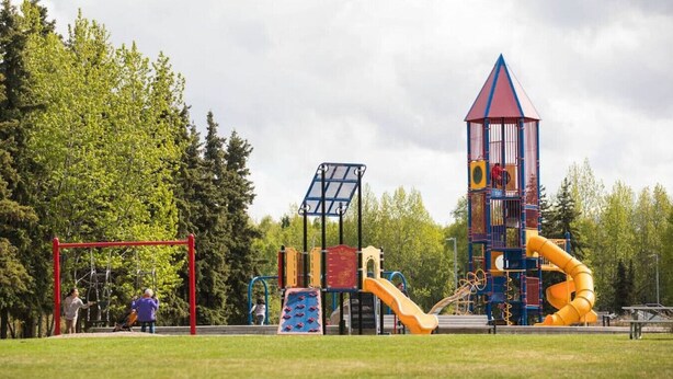 Un parque infantil con diversas estructuras de juego, incluyendo un tobogán, una zona de escalada y una torre.