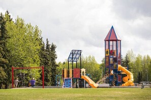 A playground with various play structures including a slide, climbing area, and a tower. - Creekside Retreat, King Bed Near Downtown & Trails, sleeps 14! (Anchorage)