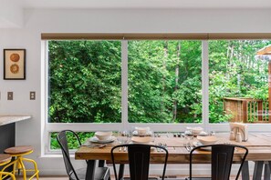 A dining area with a large window overlooking a lush green forest.