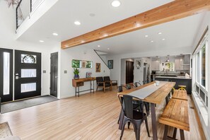 Un salón amplio con una mesa de comedor de madera, sillas negras y una cocina al fondo.