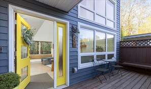 A house with a bright yellow door, a deck with outdoor furniture, and a window with the number 545.
