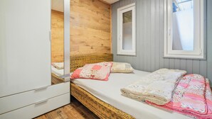 A bedroom with a wooden headboard, a large mirror, two windows, and a bed with a quilt. - Cozy home in Zeulenroda-Triebes with sauna (Zeulenroda-Triebes)