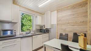 A modern kitchen with white cabinets, a built-in microwave, a coffee maker, and a window with a view of greenery. - Cozy home in Zeulenroda-Triebes with sauna (Zeulenroda-Triebes)