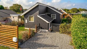 Et moderne hus i to etager med skråt tag, grusvej og træhegn.