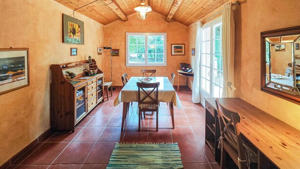 Une cuisine chaleureuse avec des meubles en bois, une table à manger et une grande fenêtre.