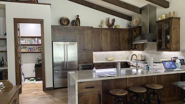 Eine moderne Küche mit Holzschränken, Edelstahlgeräten und einer zentralen Kochinsel mit Sitzgelegenheiten.