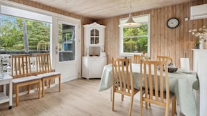 Un interior de madera con una mesa de comedor, sillas, un armario blanco y un reloj en la pared.