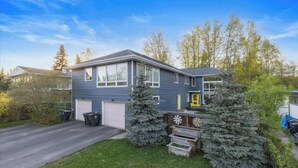 Ett tvåvåningshus med garage, en liten trädgård framför huset med ett litet träd och en träveranda.