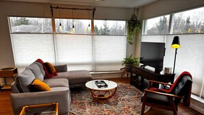 Ett vardagsrum med en soffa, en fåtölj, ett soffbord och en tv.