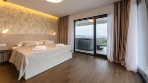 A modern hotel room with a large bed, a marble-patterned wall, and a balcony with a city view. - Nice home in Kastel Stari with sauna (Kastel Stari)