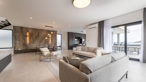 A modern living room with a sofa, armchairs, a coffee table, and a dining area with chairs and a table. There is a kitchen area in the background and a balcony with a view. - Nice home in Kastel Stari with sauna (Kastel Stari)