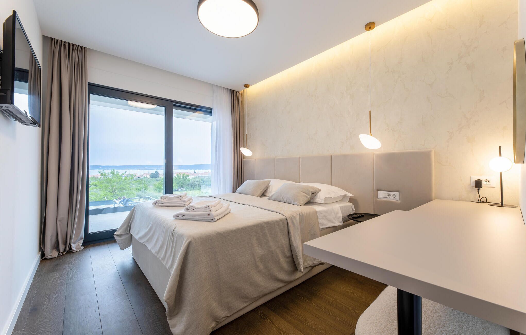 Une chambre d’hôtel moderne, dotée d’un grand lit, de tables de chevet, d’un bureau et offrant une vue sur la ville.