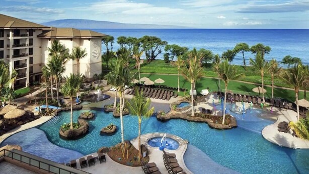 Ein Resort mit mehreren Swimmingpools, Palmen und Blick aufs Meer.