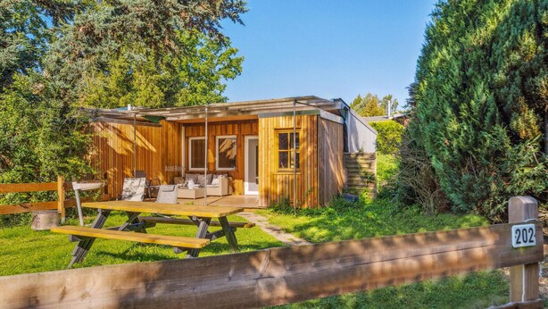 Une cabane en bois dotée d’une terrasse, d’une table de pique-nique et d’un espace clôturé.