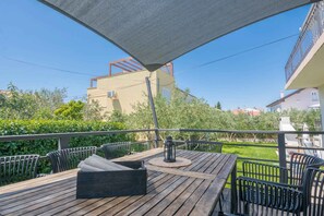 An outdoor patio with wooden furniture, a table, and chairs. - Holiday apartment mit Terrasse (Biograd na Moru)