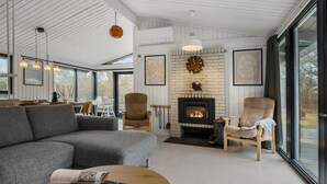 A modern living room with a fireplace, large windows, and a cozy seating area. - Nice home in Fårevejle with WiFi (Fårevejle)