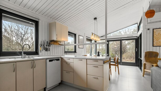 A modern kitchen with a dishwasher, a large window, and a dining area with a chair. - Nice home in Fårevejle with WiFi (Fårevejle)