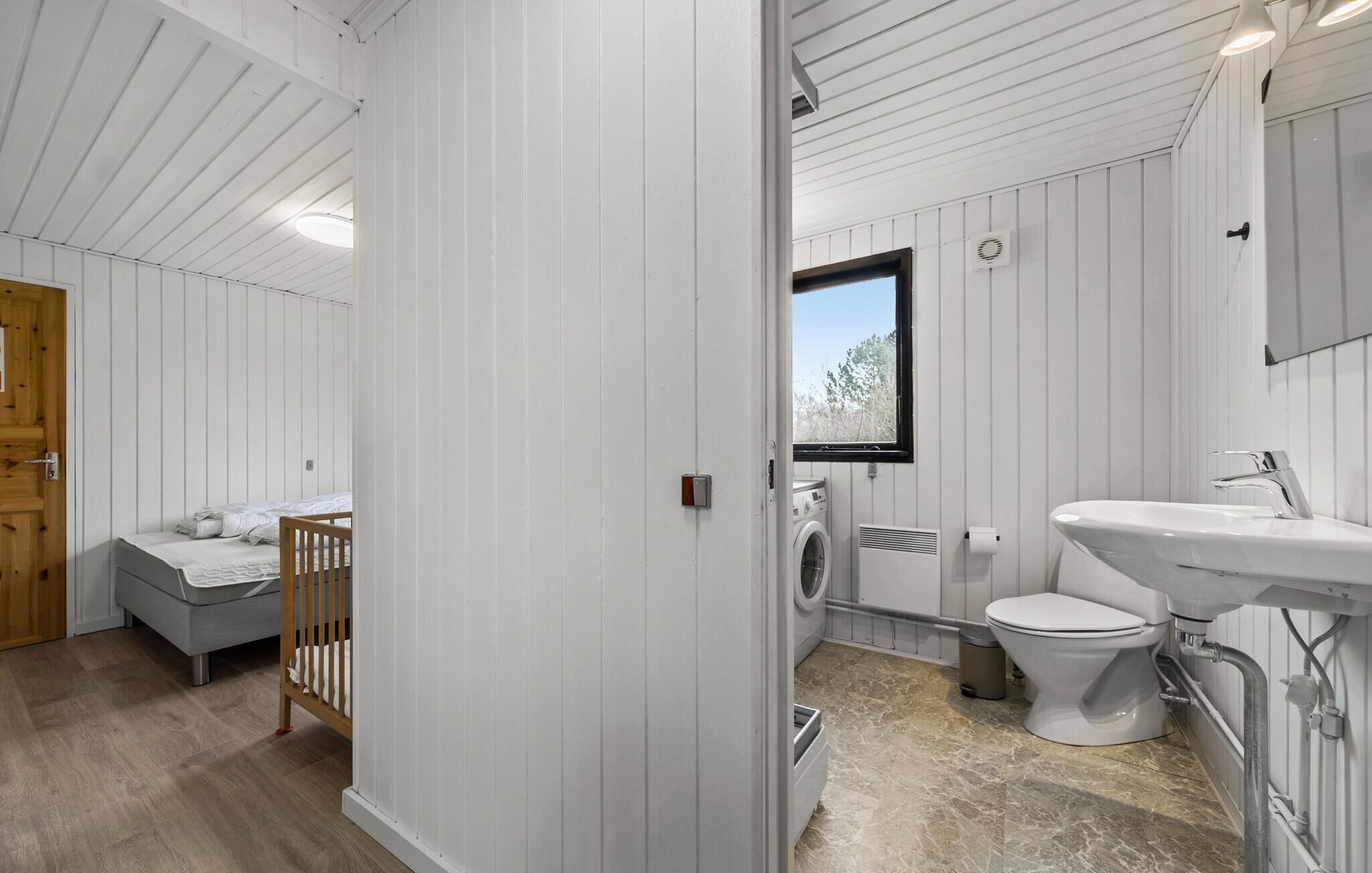 Ein kleines, weißes Badezimmer mit Waschmaschine, Toilette und Waschbecken.
