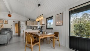 A modern kitchen with wooden cabinets, a dining table with chairs, and pendant lighting. - Nice home in Fårevejle with WiFi (Fårevejle)