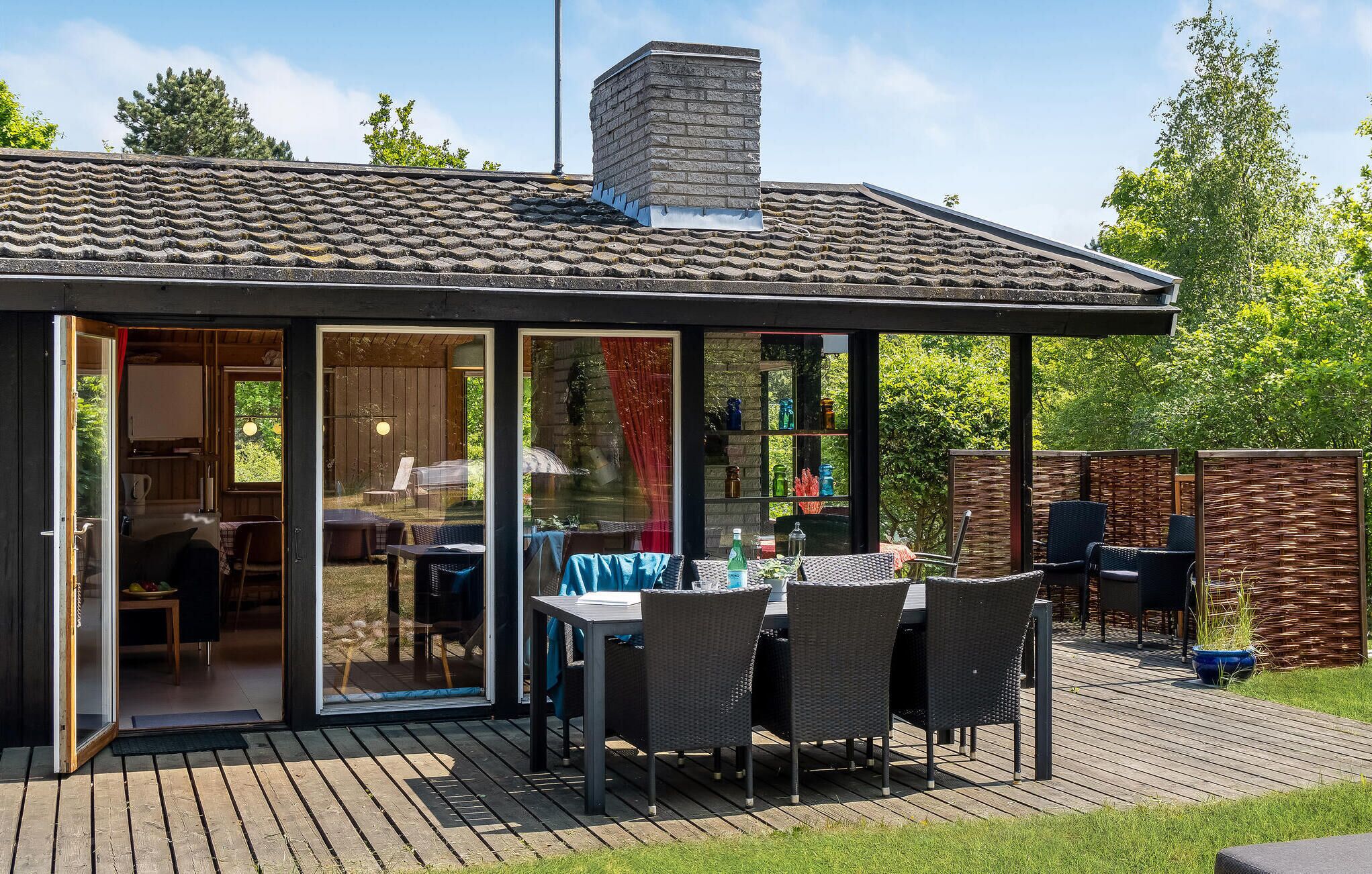 A covered patio with a table and chairs, a chimney, and a view of the backyard.