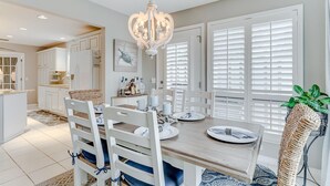 Une cuisine moderne avec des meubles blancs, une table à manger en bois et un lustre.