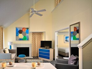 Ein Hotelzimmer mit einer Couch, einem Couchtisch, einem Fernseher, einem Kamin und Wandbildern.