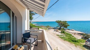 En balkon med havudsigt, en stol og et bord med ting på.