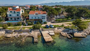 En ejendom ved kysten med swimmingpool, stenvægge og klart vand.