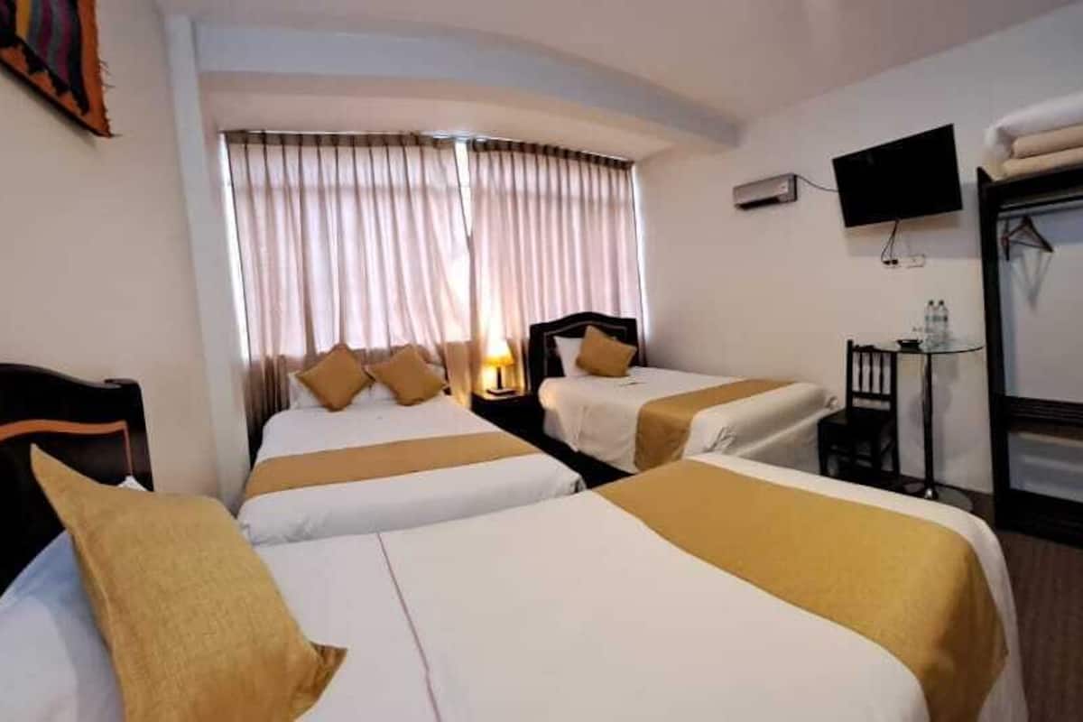 A hotel room with two beds, a TV, a desk, and a wardrobe.