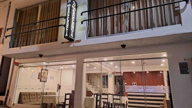 Un hotel con fachada de vidrio, una recepción visible y una escalera que conduce a un piso superior.
