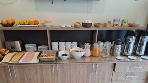 Una encimera de cocina con artículos de desayuno, como frutas, cereales y cafeteras.
