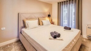 A hotel room with a large bed, a bedside lamp, a window with curtains, and a wall-mounted air conditioner. - Holiday apartment with pool and air conditioning (Njivice)
