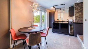 A modern kitchen with a built-in oven, a dining area with a round table and chairs, and a large window providing a view of the outdoors. - Holiday apartment with pool and air conditioning (Njivice)