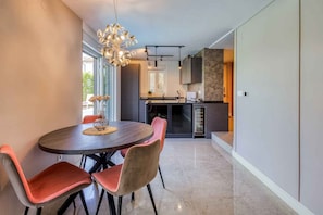 A modern kitchen with dark cabinetry, a central island, and a dining area with a round table and chairs.