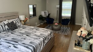A bedroom with a bed, a ceiling fan, a desk with a chair, a potted plant, and a vase with flowers.
