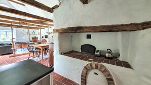 A rustic kitchen with exposed wooden beams, a brick oven, and a dining area with a table and chairs. - 2 bedroom cozy home in Munka Ljungby (Munka Ljungby)
