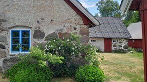 A rustic stone building with a blue window and a red door, surrounded by greenery and a clear sky. - 2 bedroom cozy home in Munka Ljungby (Munka Ljungby)