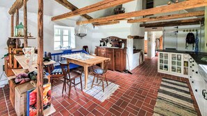 A rustic kitchen with exposed wooden beams, a dining area with a wooden table and chairs, and a brick floor. - 2 bedroom cozy home in Munka Ljungby (Munka Ljungby)