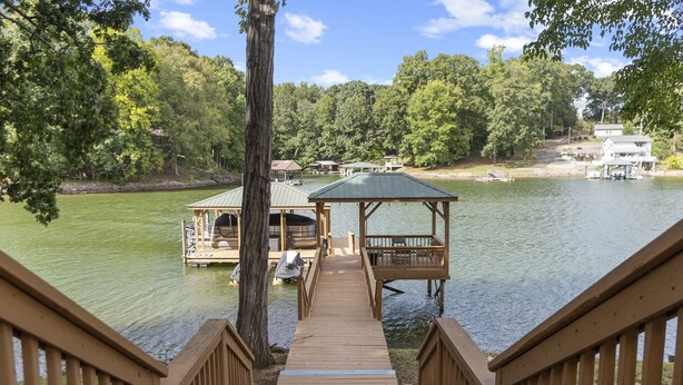 A wooden dock leading to a gazebo over water, surrounded by trees and a house in the background. - Hideaway Hill - Lakefront Relaxation with Great Amenities (Denver)