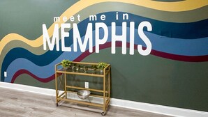 A wall with the text "meet me in MEMPHIS" and a gold-framed display case with decorative items.