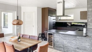 A modern kitchen with a built-in island, stainless steel appliances, and a stone backsplash. - 3 bedroom cozy home in Gotlands Tofta (Gotlands Tofta)