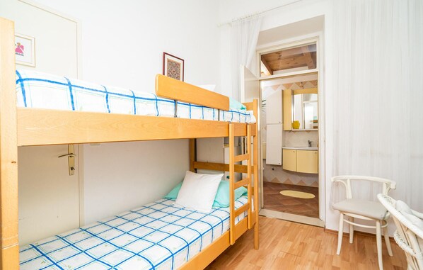 Un lit superposé avec une couverture à carreaux, une échelle en bois et un petit bureau avec une chaise.