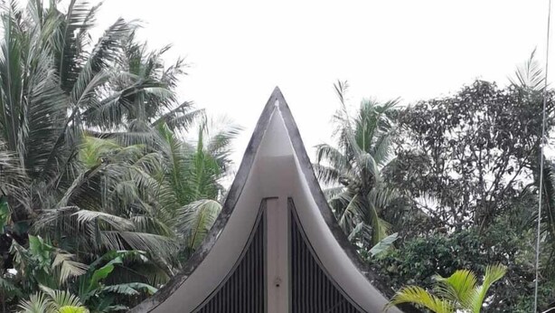 Un bâtiment moderne doté d’un toit triangulaire original et d’une entrée centrale.