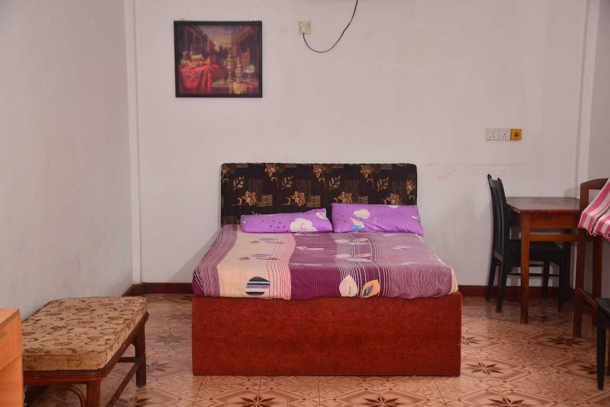 Une chambre à coucher avec un lit, une chaise, une table et un tableau accroché au mur.