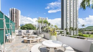A rooftop terrace with outdoor seating, a pool, and a view of surrounding buildings.