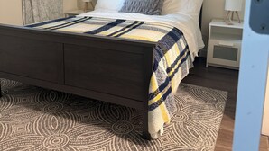 Ein Schlafzimmer mit einem Bett, Nachttischen, einem Gemälde und einem gemusterten Teppich.