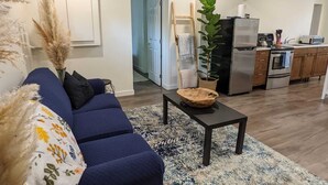 Ein modernes Wohnzimmer mit einem dunkelblauen Sofa, einem Couchtisch und einer großen Pflanze.