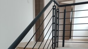 A staircase with black railings and beige steps leading to an upper floor. - Modern 2 Bedroom Duplex - Gated Estate , 24/7 Security, Gym, Pool, Tennis Court (Tema)