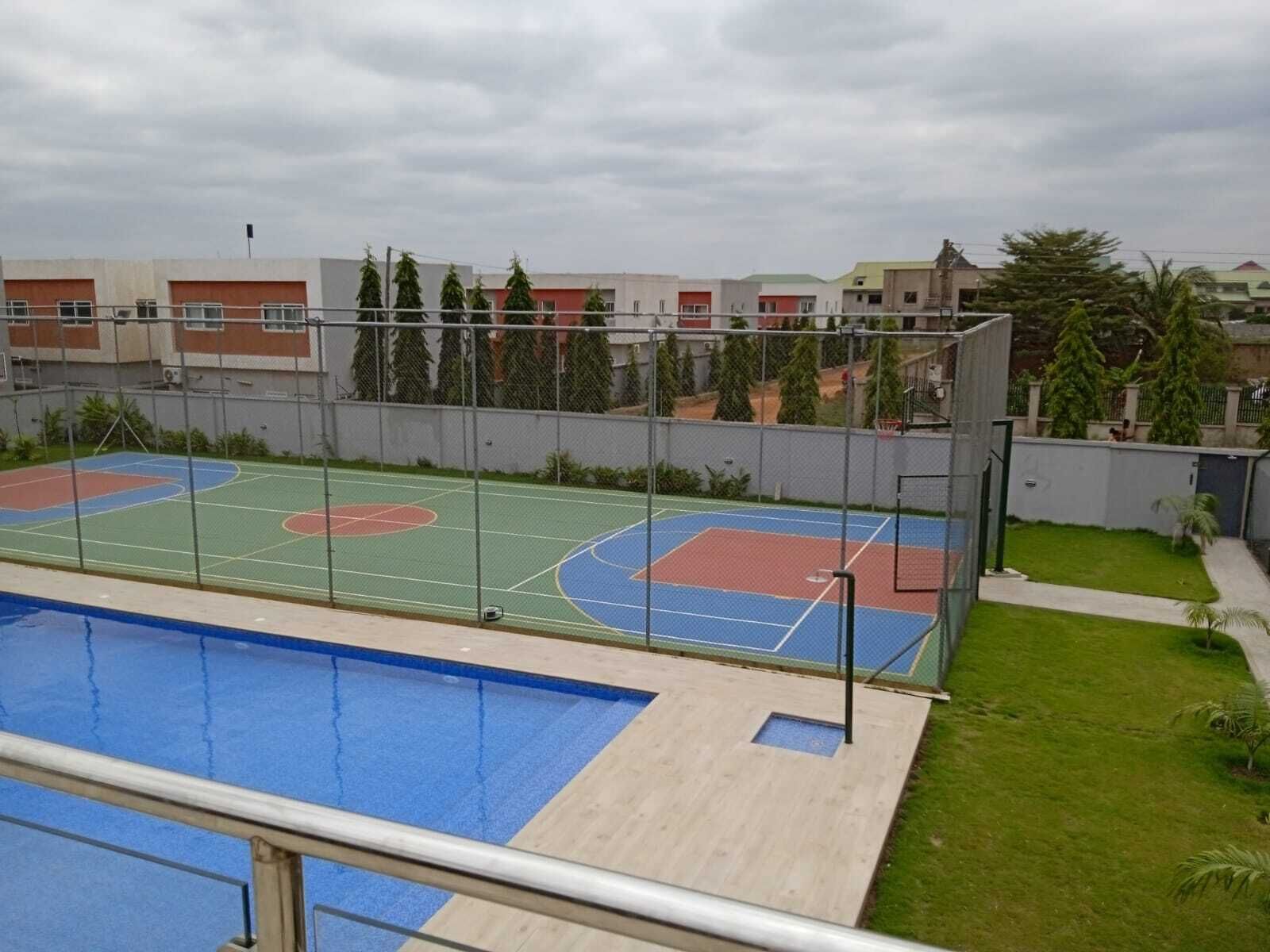 A rooftop sports facility with a basketball court and a swimming pool.